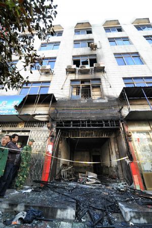 People gather at the site of a fire in Chaling County, Zhuzhou city, central China's Hunan Province, Dec. 22, 2009. The fire broke out here on Tuesday morning and killed 7 people.