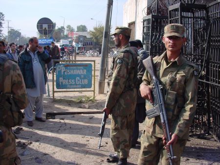 Security personnel stand guard at the site of blast in the northwestern Pakistani city of Peshawar, Dec. 22, 2009. A suicide attacker blew himself up outside the Peshawar Press Club when he was stopped by police at the entrance. Three persons, including a police officer, were killed and 17 others injured.(Xinhua/Saeed Ahmad)