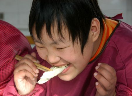A student tastes a dumpling made by herself at Xingtai Special Education School in Xingtai of north China&apos;s Hebei Province, Dec. 22, 2009. 2009. The Winter Solstice Festival, a traditional day for eating dumplings in China, arrived on Tuesday. Volunteers of Xingtai Charity Association came to the school and made dumplings with the students there.(Xinhua/Huang Tao)