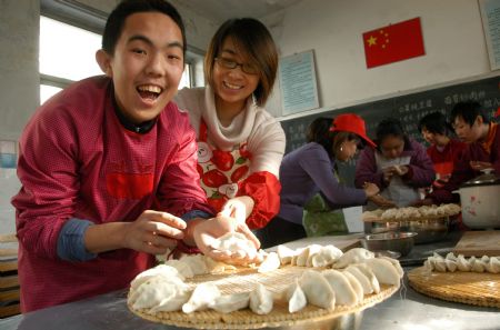 A student (L) makes dumplings with a volunteer at Xingtai Special Education School in Xingtai of north China&apos;s Hebei Province, Dec. 22, 2009. 2009.(Xinhua/Huang Tao)