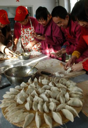 Students make dumplings in the help of volunteers at Xingtai Special Education School in Xingtai of north China&apos;s Hebei Province, Dec. 22, 2009. 2009. (Xinhua/Huang Tao)