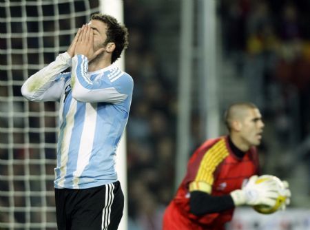 Argentina&apos;s Angel Di Maria (L) reacts against Catalunya&apos;s goalkeeper Victor Valdes during a friendly soccer match at Camp Nou stadium in Barcelona December 22, 2009.