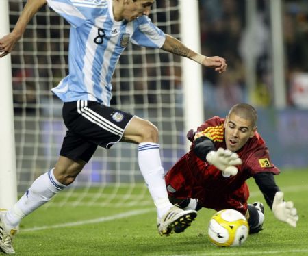 Argentina&apos;s Angel Di Maria (L) fights for the ball against Catalunya&apos;s goalkeeper Victor Valdes during a friendly soccer match at Camp Nou stadium in Barcelona December 22, 2009. 