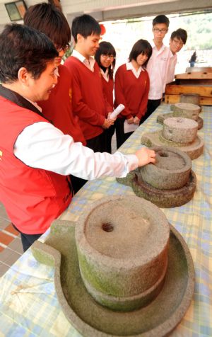 Students and teachers watch the ancient kitchenwares displayed in an activity of making sweet soup dumplings at a middle school in Taipei, southeast China&apos;s Taiwan.