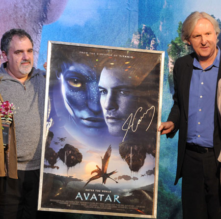 Canadian film director James Cameron (R) shows a poster of his latest film "Avatar" with producer Jon Landau during a press conference in Beijing, capital of China, on Dec. 23, 2009. "Avatar" is the story of an ex-Marine who finds himself thrust into hostilities on an alien planet filled with exotic life forms. The film is scheduled to debut on Jan. 4, 2010 in China. (Xinhua/Jin Liangkuai)