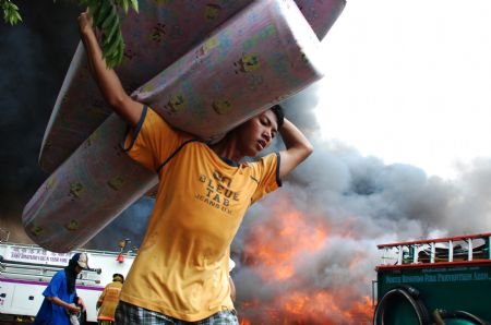 A resident tries to save his belongings from a fire on the suburb of Manila, the Philippines, Dec. 23, 2009. 