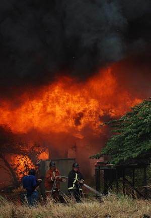 Firemen extinguish fire on the suburb of Manila, the Philippines, Dec. 23, 2009. At least 600,000 shanties and hundreds of families were affected. (Xinhua/Jonas Sulit)