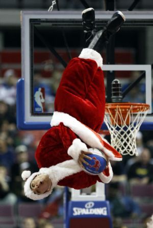 A member of the Detroit Pistons &apos;Flight Crew&apos; dunk team, wearing a Santa suit, flips upside down before dunking a ball during a time-out in the first half of their NBA basketball game against the Toronto Raptors in Auburn Hills, Michigan December 23, 2009. 