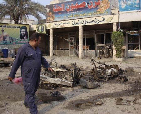 A resident looks at the wreckage of a car bomb after bomb attacks in Hilla, 100 km (62 miles) south of Baghdad, December 24, 2009.(Xinhua/Reuters Photo)