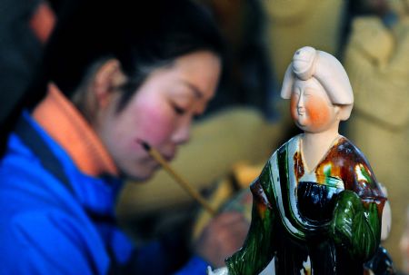 A worker paints a three-color glazed figurine at a workshop in Nanshishan Village, Mengjin County of central China&apos;s Henan Province, Dec. 24, 2009. The village, boasting archaized craftwork that gains great popularity among buyers both from China and abroad, claims an annual output value of over 75 million yuan (about 10.8 million U.S. dollars). (Xinhua/Wang Song)