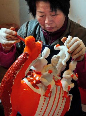 A worker glazes an archaized figurine at a workshop in Nanshishan Village, Mengjin County of central China&apos;s Henan Province, Dec. 24, 2009.(Xinhua/Wang Song)