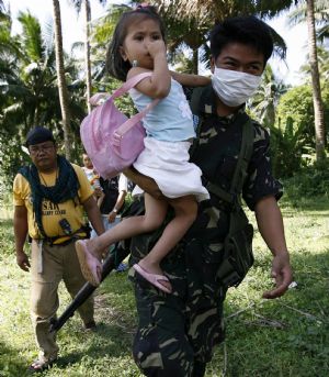 A soldier carries a girl during a forced evacuation near the Mayon volcano in Guinobatan town, Albay province, south of Manila December 24, 2009. The Philippines&apos; most active volcano shot higher ash columns and rumbled louder on Wednesday as authorities warned of a potential hazardous eruption in Mount Mayon anytime.