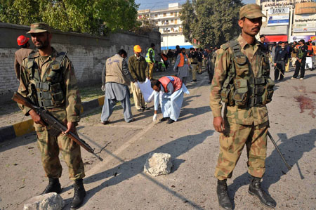 Two soldiers stand guard at the blast site in in the northwestern Pakistani city of Peshawar, Dec. 24, 2009. At least four people were killed and 11 others were indured Thursday morning in a suicide bombing in Peshawar.