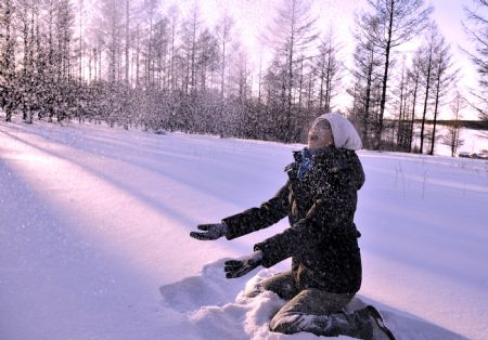 A tourist plays with snow in Yakeshi, north China&apos;s Inner Mongolia Autonomous Region, Dec. 22, 2009.(Xinhua/Li Xin)