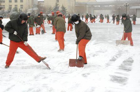 Workers clear away snow on the main road in their factory in Dalian, northeast China's Liaoning Province, Dec. 25, 2009. A strong cold wave and heavy snowfall hit Liaoning Province from Thursday night, causing a sudden temperature fall of over ten degrees Celsius. [Liu Debin/Xinhua]