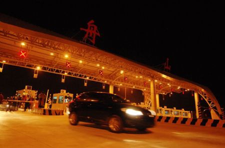 A car runs past Shuangqiao toll gate of the Zhoushan Sea-crossing Bridge in Zhoushan, east China's Zhejiang Province, Dec. 26, 2009. Costing 13.1 billion RMB yuan (US$1.9 billion) the 46.5-kilometer Zhoushan Sea-crossing Bridge, so far the longest of its kind in the country, has been completed after 10 years of construction since Sept. 1999. The sea-crossing bridge linking Zhoushan City, China's only city of more than 1,000 islands, went into trial operation on Friday.