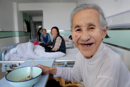 Mao Yuye, 82, smiles to camera in this file photo taken on May 25, 2009 at a hospital in Shenmu County, northwest China's Shaanxi Province. Mao paid only 40yuan(5.5 U.S. dollars) for her near 10,000 yuan medical bill as the local goverment implements a package of social welfare program. What the coal-rich county with 400,000 people offers is not only free medical service to its people, but also 12 years of free education for all children, better housing for farmers and urban poor, and poverty relief. (Xinhua/Tao Ming)