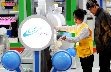 A shop assistant (L) introduces to a customer energy-saving lamps at a supermarket in Beijing, capital of China, Dec. 26, 2009. The first batch of two energy-saving product supermarkets were opened in Beijing on Friday. (Xinhua) 