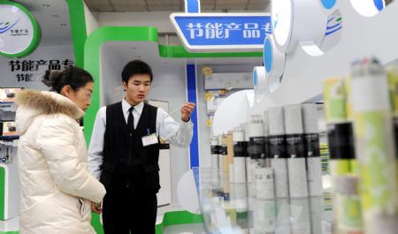 A shop assistant (R) introduces to a customer energy-saving stationeries at a supermarket in Beijing, capital of China, Dec. 26, 2009. The first batch of two energy-saving product supermarkets were opened in Beijing on Friday. (Xinhua)