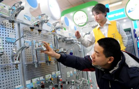  A customer looks at a water-saving faucet at a supermarket in Beijing, capital of China, Dec. 26, 2009. The first batch of two energy-saving product supermarkets were opened in Beijing on Friday. (Xinhua)