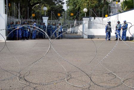 Security personnels stand guard in front of Raj Bhavan in Hyderabad on Dec. 26, 2009 as members of women organizations demonstrating to demand the punishment on N.D.Twari, the Governor of Indian state of Andhra Pradesh, on his alleged involvement in sex scandal. The Governor of Andhra Pradesh N.D.Twari resigned on Saturday.
