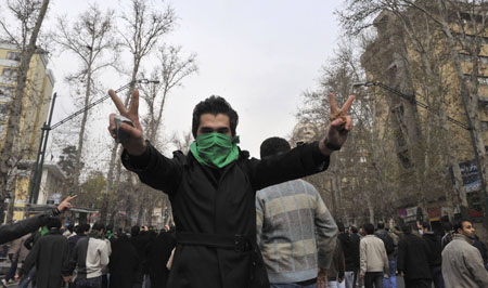 An Iranian protestor with his face covered with a green mask flashes the victory sign as he holds stones in his hands during clashes in central Tehran December 27, 2009. 