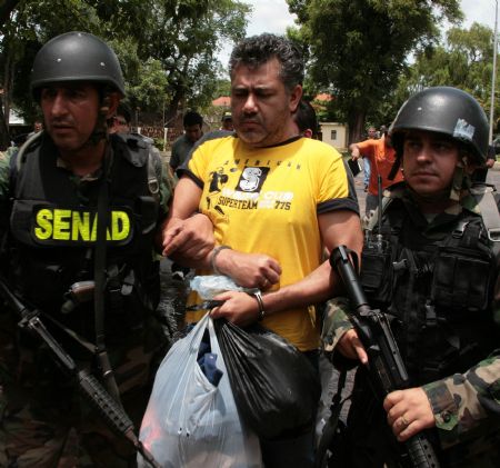 Policemen escort drug dealer Jarvis Chimenes Pavao (2nd R) to custody in Asuncion, capital of Paraguay, Dec. 27, 2009.