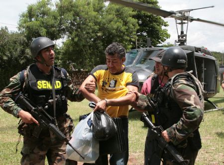 Policemen escort drug dealer Jarvis Chimenes Pavao (2nd L) to custody in Asuncion, capital of Paraguay, Dec. 27, 2009.