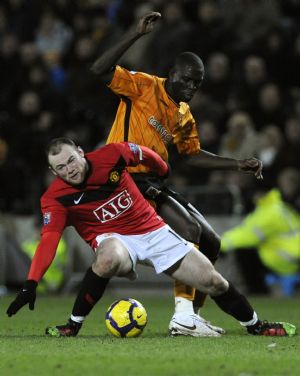 Hull City's Seyi Olofinjana (R) challenges Manchester United's Wayne Rooney during their English Premier League soccer match in Hull, northern England December 27, 2009.