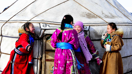 Girls of Mongolian ethnic group laugh in front of a Monglian yurt in Xi Ujimqin Qi, north China's Inner Mongolia Autonomous Region, on Dec. 28, 2009. (Xinhua/Ren Junchuan)