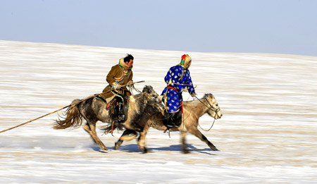 Herdsmen of Mongolian ethnic group preform equestrian skills in Xi Ujimqin Qi, north China's Inner Mongolia Autonomous Region, on Dec. 28, 2009. (Xinhua/Ren Junchuan)