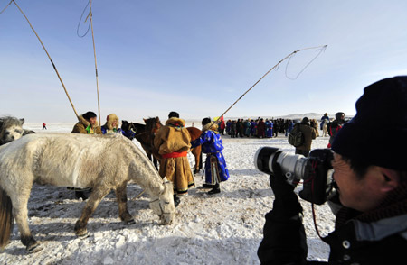 A photographer takes photos of the ice and snow carnival in Xi Ujimqin Qi, north China's Inner Mongolia Autonomous Region, on Dec. 28, 2009. (Xinhua/Ren Junchuan)