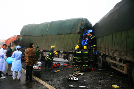 Photo taken on Dec. 28, 2009 shows rescuers work at the traffic accident site on the Poyang Lake Bridge in east China's Jiangxi Province. At least 10 people died and 19 were injured Monday in a series of rear-end collisions, involving at least 100 vehicles, on the Poyang Lake Bridge, part of the Jiujing Highway linking Jiujiang City to Jingdezhen City, said a Provincial Communications Department official. The low visibility in the heavy fog and the ice on the bridge were blamed for the accidents, the official said.(Xinhua Photo)