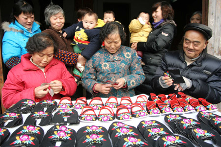 Folk handicraftsmen make "Tiger Shoes", traditional Chinese cloth shoes for children, in Taoshan Township in Hanshan County, east China