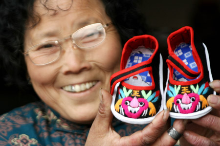 Zhang Congyu, a folk handicraftswoman, shows her handmade "Tiger Shoes", traditional Chinese cloth shoes for children, in Taoshan Township in Hanshan County, east China
