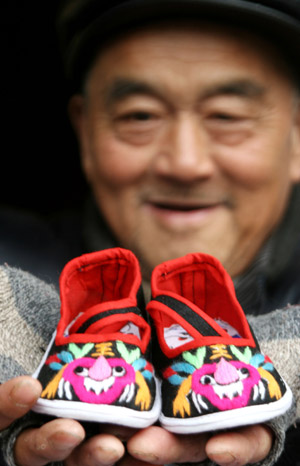 Zhou Changfa, a folk handicraftsman, shows his handmade "Tiger Shoes", traditional Chinese cloth shoes for children, in Taoshan Township in Hanshan County, east China