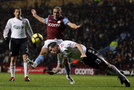 Liverpool's Jamie Carragher (R) heads clear of Aston Villa's Luke Young (C) during their English Premier League soccer match at Villa Park in Birmingham, central England, December 29, 2009. Liverpool defeats Aston Villa with 1-0.(Xinhua/Reuters Photo)