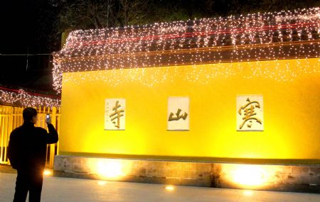 A man takes photo of the stone archway at the facade of the Hanshan Temple which flares and scintillates in grand illumination, in Suzhou, east China&apos;s Jiangsu Province, Dec. 29, 2009.[Wang Jianzhong/Xinhua]