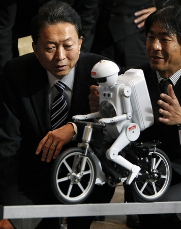 Japan&apos;s Prime Minister Yukio Hatoyama watches a demonstration by humanoid robot Seisaku-kun after a news confernce to announce the government&apos;s new growth strategy, at his official residence in Tokyo December 30, 2009. [China Daily via Agencies]