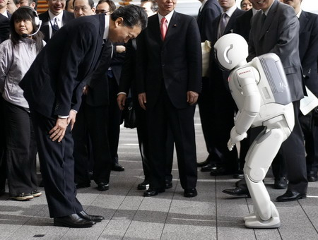 Japan&apos;s Prime Minister Yukio Hatoyama (L) bows to Honda&apos;s humanoid robot Asimo during its demonstration after a news conference to announce the government&apos;s new growth strategy, at his official residence in Tokyo December 30, 2009. [China Daily via Agencies]