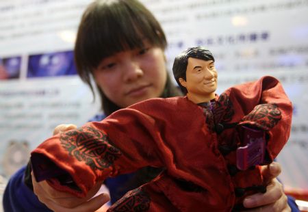 A girl presents a mini statue of Kungfu star Jackie Chan, at the ongoing 1st China International Animation Copyright Fair, which opens at the International Convention and Exhibition Center of Dongguan, south China&apos;s Guangdong Province, Dec. 30, 2009.[Chen Fan/Xinhua]