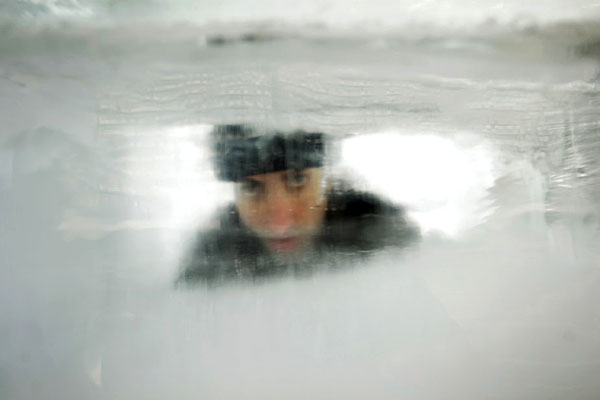 Israeli magician Hezi Dean peers from inside an eight-tonne block of ice at Rabin Square in Tel Aviv December 29, 2009. In an attempt to break David Blaine&apos;s November 2000 record, Dean plans to stay in the ice for 64 hours and emerge at midnight on December 31. [Chinanews.com.cn]