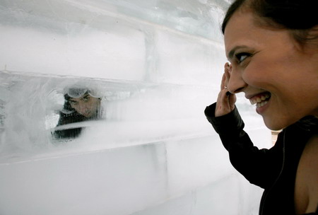 A woman waves to Israeli magician Hezi Dean peering from inside an eight-tonne block of ice at Rabin Square in Tel Aviv December 29, 2009.[Chinanews.com.cn]