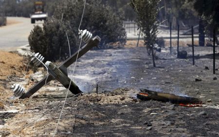 A power pole, destroyed by bushfire, smoulders on the ground near Toodyay about 75km (47 miles) north east of Perth December 30, 2009. A major bushfire in the west Australian outback has destroyed almost 40 homes, officials said on Wednesday, as firefighters end a third month of fighting bushfires across the country.