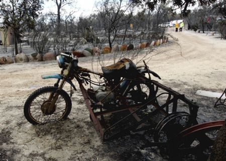 A motorcycle and a sidecar, destroyed by bushfire, stand beside a road where houses have been destroyed near Toodyay about 75km (47 miles) north east of Perth December 30, 2009. A major bushfire in the west Australian outback has destroyed almost 40 homes, officials said on Wednesday, as firefighters end a third month of fighting bushfires across the country. 