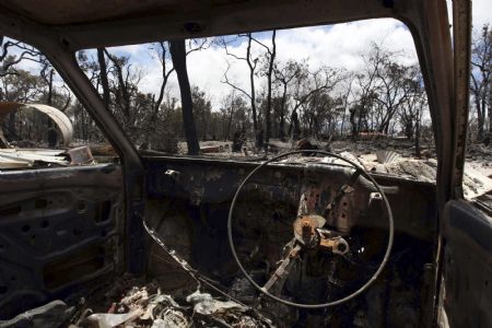 A property, destroyed by bushfire, is framed by a burned out car near Toodyay about 75km (47 miles) north east of Perth December 30, 2009. A major bushfire in the west Australian outback has destroyed almost 40 homes, officials said on Wednesday, as firefighters end a third month of fighting bushfires across the country. 