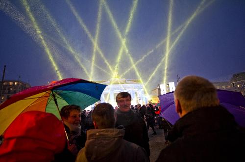 Revellers with umbrellas gather attend the public party as Berlin's landmark Brandenburg Gate and 'Strasse des 17. Juni' avenue are illuminated to celebrate the New Year on late December 31, 2009.