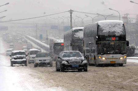 Cars move slowly on the Third Ring Road in Beijing, China, Jan. 3, 2010. Heavy snow hit Beijing on Sunday to close expressways, delay flights and disrupt bus services. (Xinhua/Tang Zhaoming)