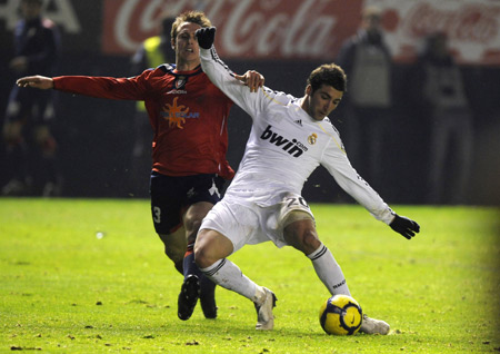 Real Madrid's Gonzalo Higuain (R) fights for the ball against Osasuna's Roberto Fernandez during their Spanish first division soccer league match at Reyno de Navarra stadium in Pamplona, Jan. 3, 2010. The match ended in a goalless draw.(Xinhua/Reuters Photo) 