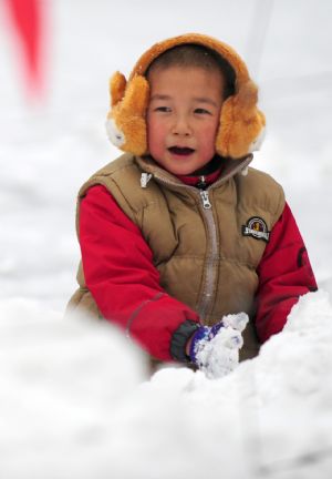 A child plays with snow in Qingcheng Park in Hohhot, north China's Inner Mongolia Autonomous Region, Jan. 3, 2010. (Xinhua/Ren Junchuan)